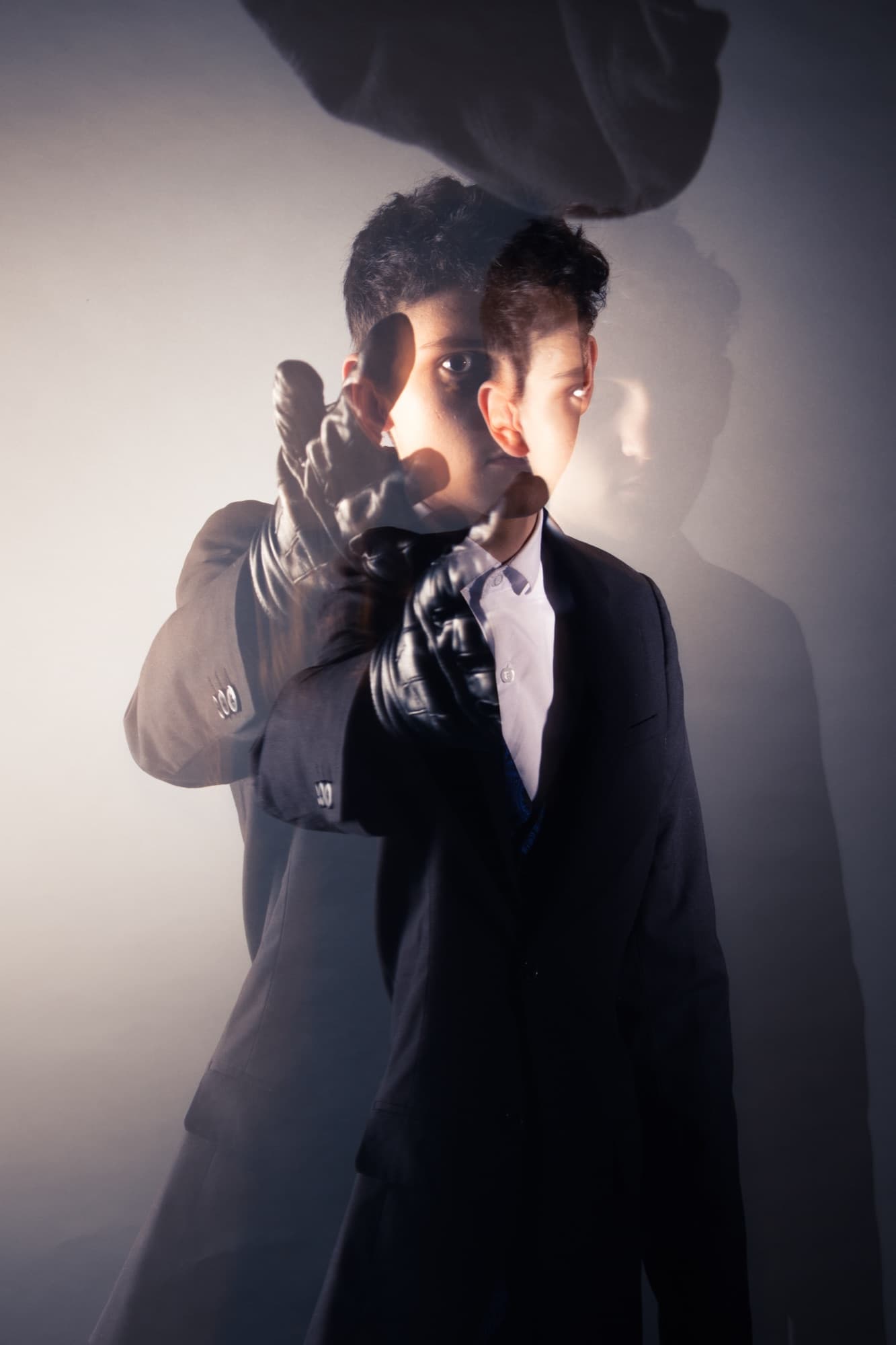 A double-exposure portrait, dark suit and leather gloves