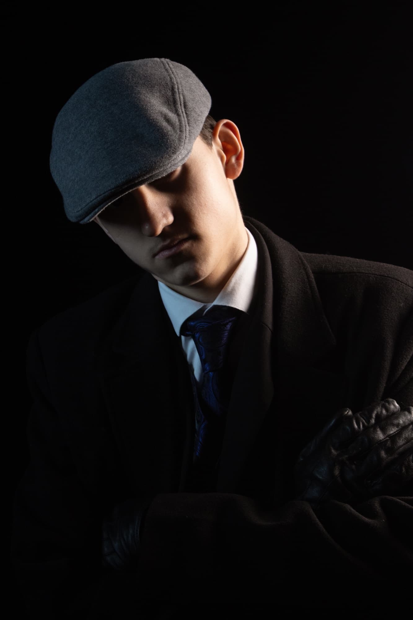 A low-key portrait, flat cap and dark suit